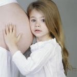 Child leaning against moms pregnant belly for Maternity Insurance